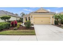 Charming yellow home featuring a two-car garage, well-manicured landscaping, and a welcoming front entrance at 11415 Fort Lauderdale Pl, Venice, FL 34293