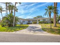 Charming single-story home with a well-maintained front yard, lush landscaping, and a curved driveway at 1220 Lakeside Dr, Venice, FL 34293