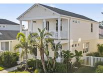 Inviting two-story home with a charming balcony, lush tropical landscaping, and a classic white picket fence at 12679 Sagewood Dr, Venice, FL 34293