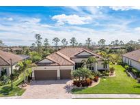 Beautiful single-Gathering home featuring a tile roof, three-car garage and lush tropical landscaping at 13325 Caravaggio Ct, Venice, FL 34293