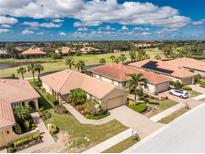 Beautiful aerial view of homes with barrel tile roofs and landscaped yards near a golf course and lake at 142 Palazzo Ct, North Venice, FL 34275