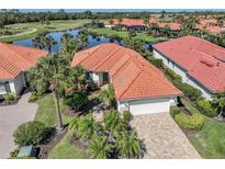 Beautiful home featuring a tile roof, paver driveway, lush landscaping, and a serene water view at 162 Treviso Ct, North Venice, FL 34275