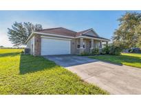 Tan single-story home featuring a two-car garage, tile roof and well maintained lawn at 17370 Cape Horn Blvd, Punta Gorda, FL 33955