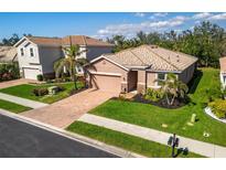 Well-manicured landscaping accents this single-Gathering home with a brick paved driveway and barrel tile roof at 2042 Mesic Hammock Way, Venice, FL 34292