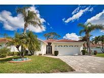 Charming home with a well-manicured lawn, beautiful palm trees, and a brick driveway leading to a two-car garage at 4398 Summertree Rd, Venice, FL 34293