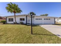 Charming single-story home featuring a well-manicured lawn, a large palm tree, and a three-car garage at 506 Buena Vista Dr, Nokomis, FL 34275