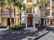 Welcoming condo building entrance featuring a decorative archway, lush landscaping, and secure access at 830 The Esplanade N # 201, Venice, FL 34285
