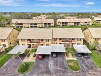 Aerial view of a two-story condo community with carports and well-maintained landscaping at 410 Mission E Trl # H, Venice, FL 34285