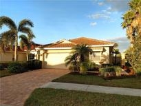 Charming single-story home with a brick driveway, lush landscaping, and mature palm trees at 102 Mestre Ct, North Venice, FL 34275