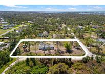Aerial view of the property with a white boundary line in a lush, wooded area with nearby water at 1871 Bridge St, Englewood, FL 34223