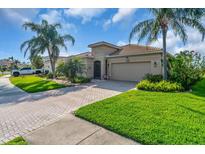 Beautiful single-story home showcasing a well-manicured lawn, brick driveway, and lush tropical landscaping at 2172 Chenille Ct, Venice, FL 34292