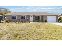 Charming one-story home with a well-manicured lawn, lovely landscaping, and an attached one car garage at 2983 Greendale Rd, North Port, FL 34287