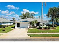 Charming single-story home with a well-manicured lawn, mature trees, and a two-car garage at 562 Silk Oak Dr, Venice, FL 34293