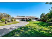 Charming home featuring an expansive green lawn and long paved driveway at 6146 Rockefeller Ave, Sarasota, FL 34231