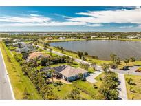 Waterfront property with a pool, solar panels and lush landscaping overlooking a serene lake at 8170 Casa De Meadows Dr, Englewood, FL 34224
