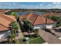 Beautiful single-story home with a tile roof, well-manicured landscaping, and a serene lake view at 9900 Haze Dr, Venice, FL 34292