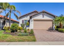 Charming single-story home featuring a well-manicured lawn, brick driveway, and a two-car garage at 10412 Crooked Creek Dr, Venice, FL 34293