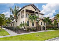 Stunning two-story home with a balcony, stone accents, mature landscaping, and a black metal fence at 158 E Tampa Ave, Venice, FL 34285