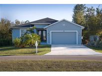 Charming one-story home with a well-manicured lawn, blue paint, and a two-car garage at 177 Ingram Blvd, Rotonda West, FL 33947