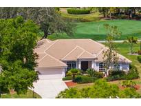 Beautiful home with a tile roof, mature landscaping, and a view of the golf course at 1995 White Feather Ln, Nokomis, FL 34275