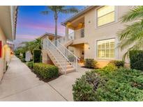 Charming exterior view of a multi-level condo complex showcasing lush landscaping and inviting entrance stairs at 4433 Corso Venetia Blvd # C18, Venice, FL 34293