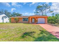 Charming single-story home with an orange exterior, well-manicured lawn, and a red concrete driveway at 491 Conrad Rd, Venice, FL 34293