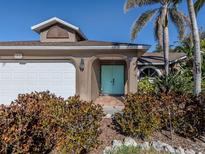 Charming home featuring a quaint front entrance with arched doorway, complemented by lush landscaping and a pop of color at 613 Sugarwood Dr, Venice, FL 34292
