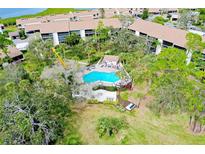 Stunning aerial view of a community pool surrounded by lush greenery and well-maintained buildings at 838 Bird Bay Way # 114, Venice, FL 34285