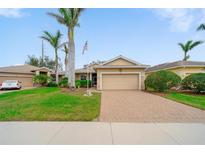 Charming single-story home featuring a well-manicured lawn, brick driveway, and beautiful palm trees at 9839 Nostalgia Pl, Englewood, FL 34223