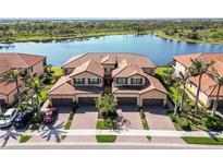 Stunning aerial view of a residential building with a tile roof situated near a serene lake and lush greenery at 10797 Tarflower Dr # 202, Venice, FL 34293