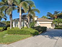 Charming single-story home featuring a manicured lawn, tropical trees, and a two-car garage at 117 Altesino Ct, Venice, FL 34292