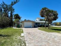 Charming single-story home with a brick driveway and mature palm trees in a sunny neighborhood at 1170 Little Ct, Englewood, FL 34223