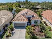 Stunning home with a tile roof, attached garage, and beautiful landscaping near a pond at 142 Braemar Ave, Venice, FL 34293