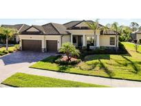 Stunning home featuring a tile roof, two-car garage, manicured lawn, and lush landscaping at 20794 Valprato Ct, Venice, FL 34293