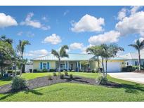 Charming home with a blue metal roof, lush green lawn, and tropical landscaping at 509 Alhambra Rd, Venice, FL 34285