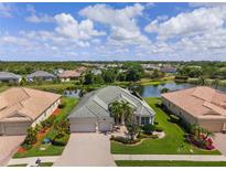 Stunning aerial view of the landscaped property with a lake, tile roof, and brick paved driveway at 5550 Rock Dove Dr, Sarasota, FL 34241
