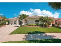 Charming single-story home with a well-manicured lawn, lush landscaping, and a paver driveway at 614 Pond Willow Ln, Venice, FL 34292