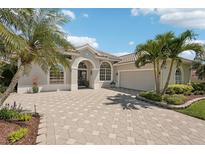 Charming single-story home featuring tropical landscaping, a paver driveway, and a two-car garage at 614 Pond Willow Ln, Venice, FL 34292