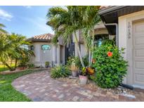 Landscaped front entrance with lush plants, palm trees, and a brick walkway leading to a beautiful home at 10139 Kansas City St, Port Charlotte, FL 33981