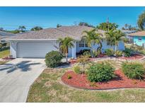 Charming single-story home with well-manicured landscaping, including palm trees and colorful mulch beds at 1048 Ulrey Ln, Englewood, FL 34223
