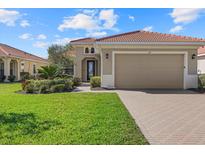 Charming home with a tile roof, paver driveway, lush landscaping, and a well-maintained lawn at 124 Pesaro Dr, North Venice, FL 34275