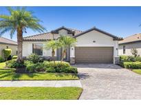 Charming home featuring a tile roof, lush landscaping, and a paved driveway at 12565 Canavese Ln, Venice, FL 34293