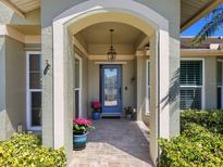 Inviting front entryway with a decorative blue door and tiled porch under a graceful archway at 1763 Cartina Way, Venice, FL 34292