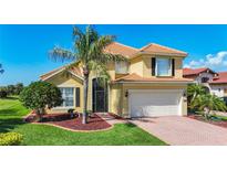 Charming two-story home featuring a terra cotta roof, a palm tree and a brick paver driveway at 23901 Waverly Cir, Venice, FL 34293