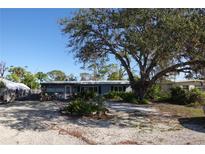Charming single-story home with a gravel yard and a large tree providing shade at 332 E Langsner St, Englewood, FL 34223