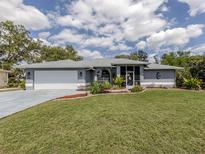 Charming single-story home with a well-manicured lawn and gray exterior and a white two-car garage at 4070 Kincord Ln, North Port, FL 34287