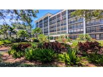 Condo building exterior featuring lush landscaping, water fountain and an American flag waving in the wind at 512 W Venice Ave # 102, Venice, FL 34285