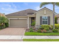Charming home featuring a tile roof, brick driveway, manicured landscaping, and a two-car garage at 11655 Renaissance Blvd, Venice, FL 34293