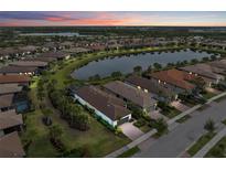 Beautiful aerial view of homes surrounding a lake, with lush landscaping and colorful sunset at 13032 Oriago St, Venice, FL 34293