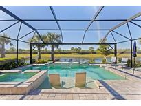 Stunning screened-in pool and spa overlooking a serene lake view with waterfall features and in-pool seating at 13251 Borrego St, Venice, FL 34293